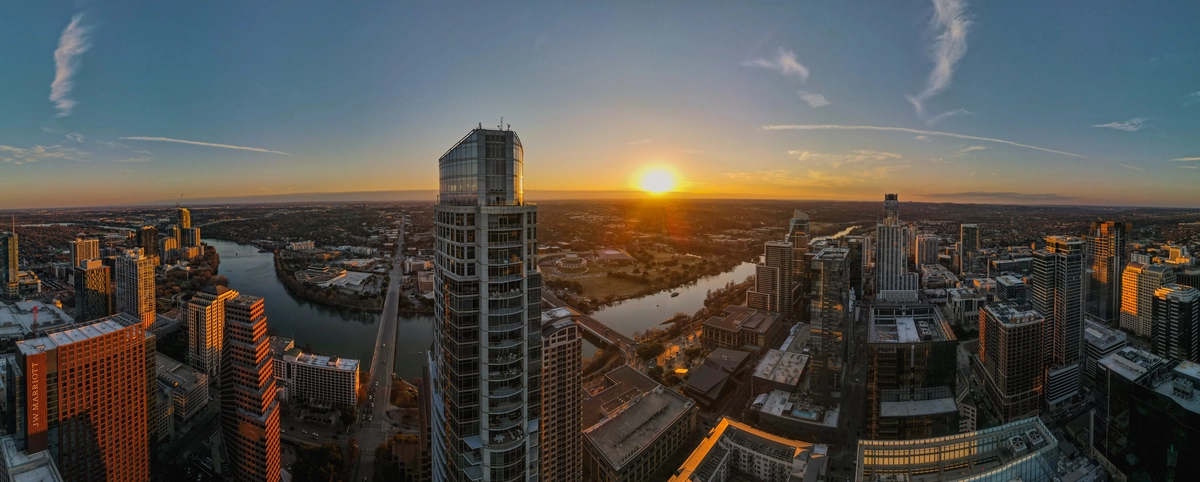 a panoramic drone image showing the Austin, Texas skyline at sunset from high in the buildings