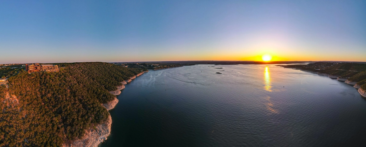 a panoramic drone image showing the Oasis and Lake Travis at sunset