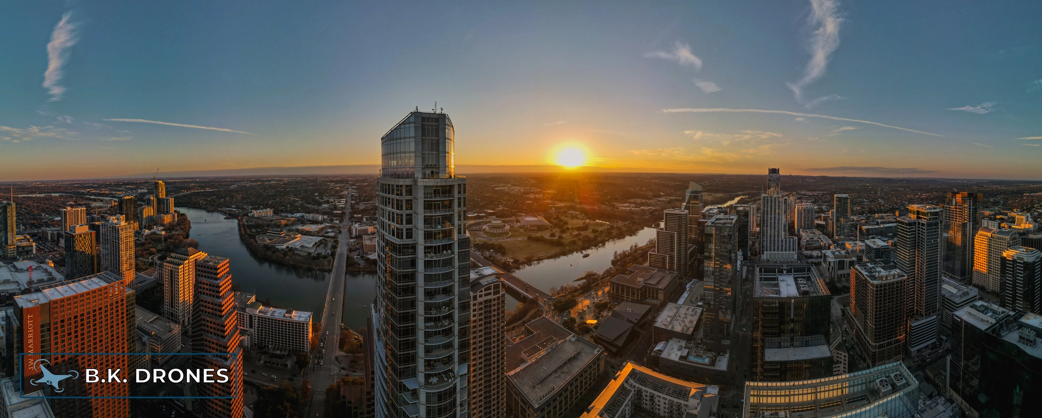 a panoramic drone image showing the Austin, Texas skyline at sunset from high in the buildings