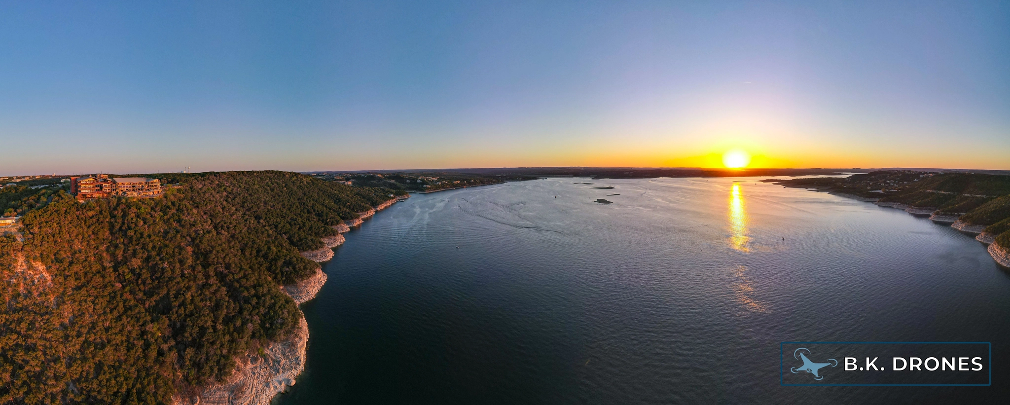 a panoramic drone image showing the Oasis and Lake Travis at sunset